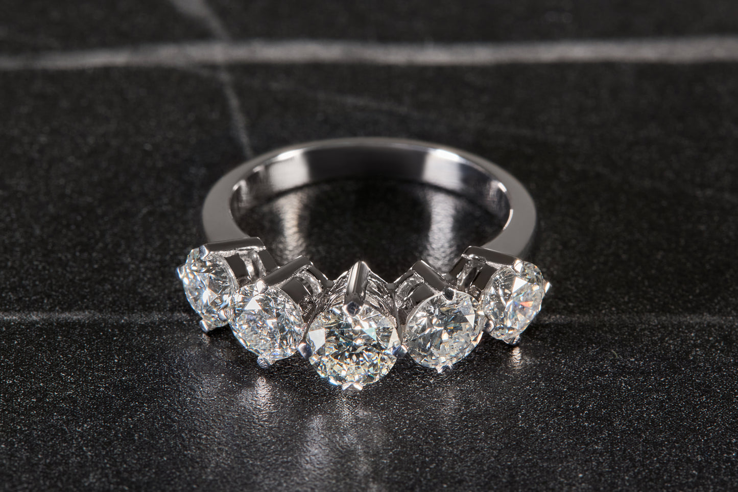 Diamond ring with five prominent stones on a black background