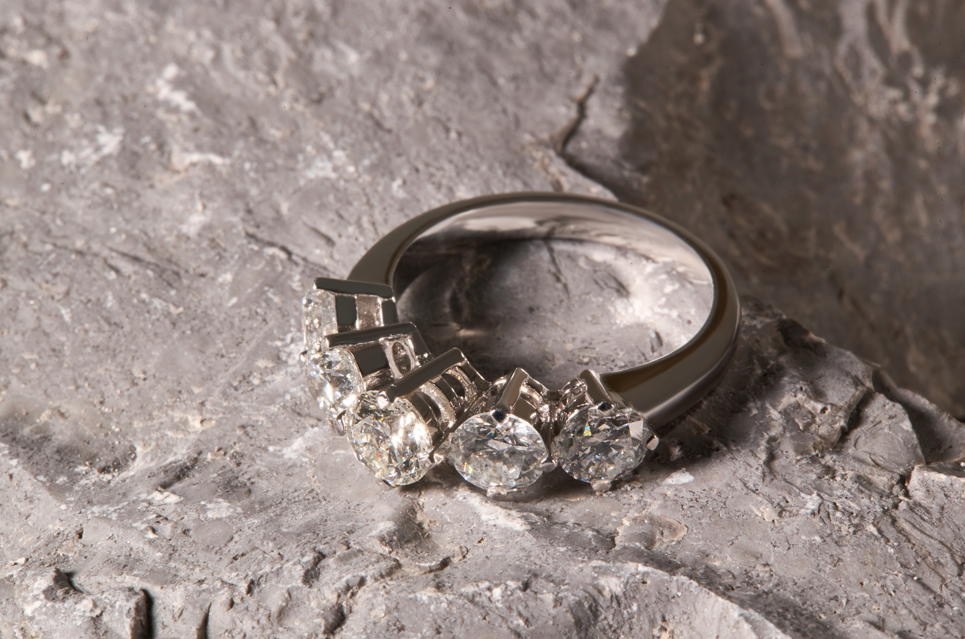 Silver diamond ring with gemstones on a textured stone surface