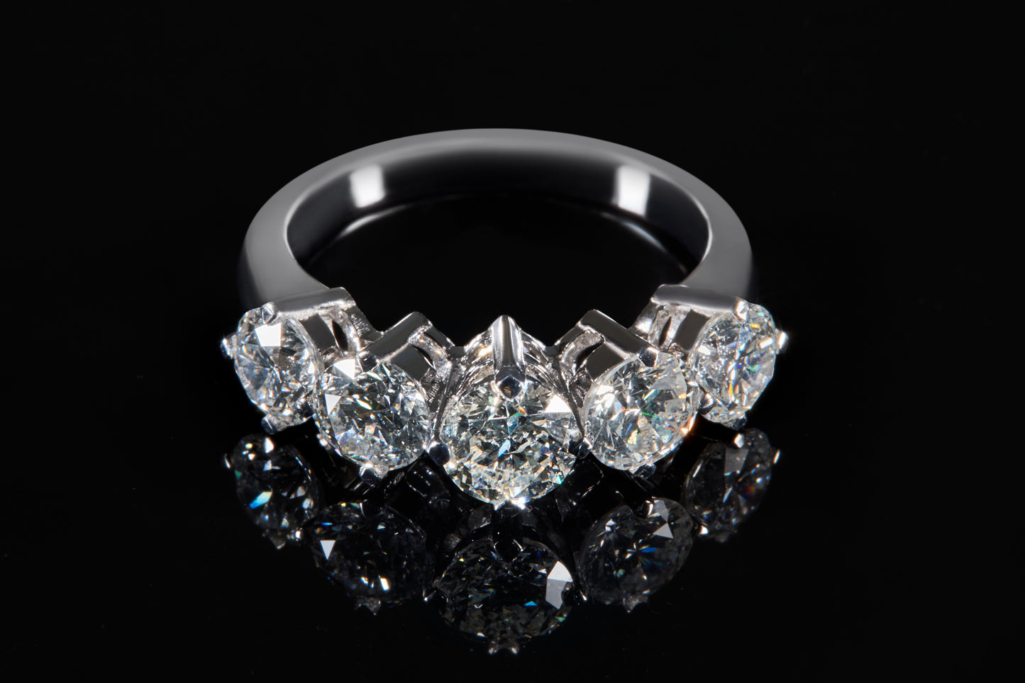 Diamond ring with five clear gemstones on a black background