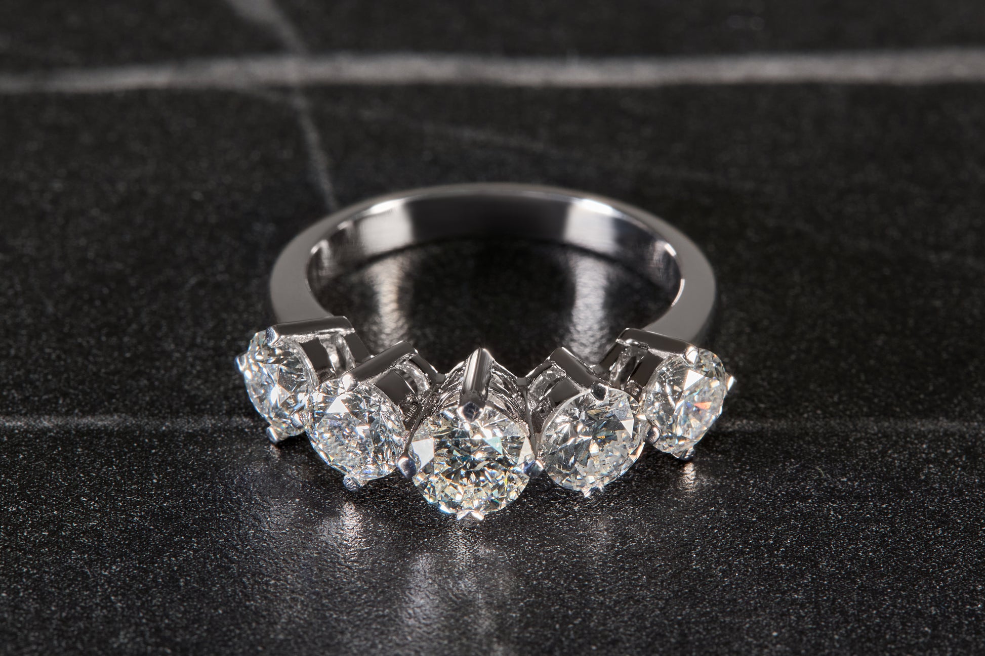 Diamond ring with five prominent stones on a black background