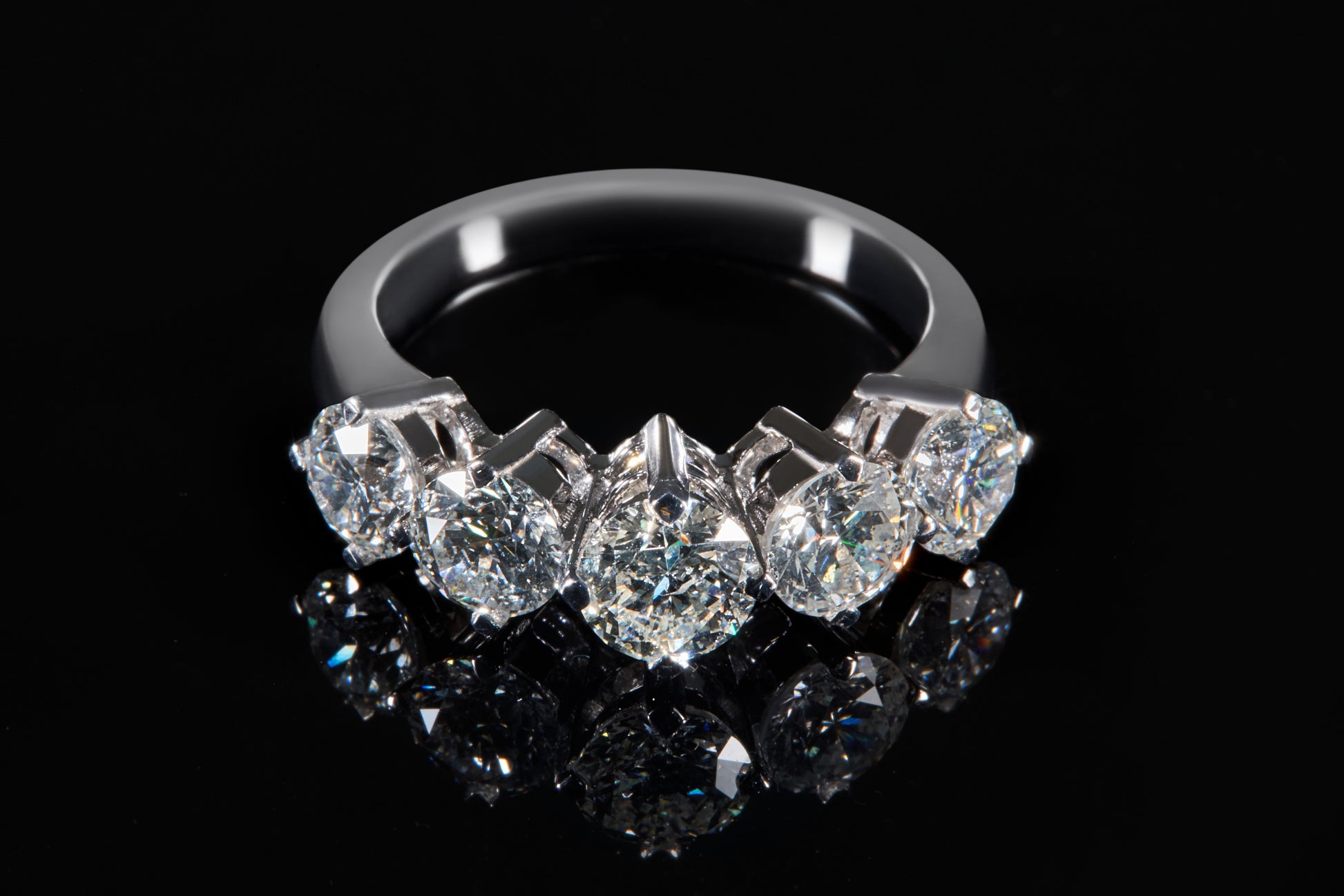 Diamond ring with five clear gemstones on a black background