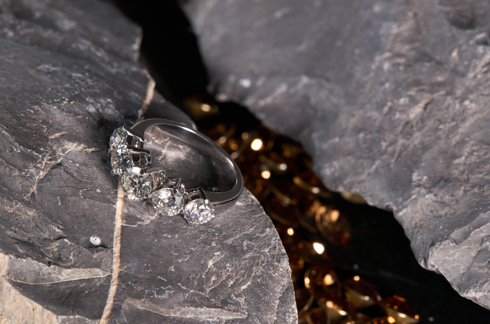Silver ring with a diamond on a dark stone surface